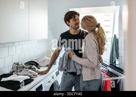 Young man flirting with girlfriend doing laundry at home Stock Photo