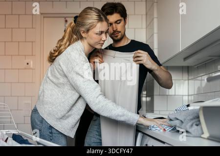 Young couple helping each other in doing laundry at home Stock Photo