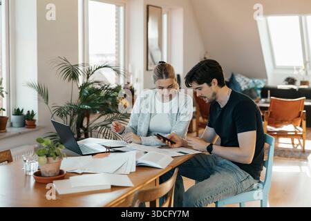 Young couple calculating savings while doing bookkeeping at home Stock Photo
