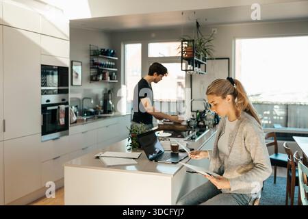 Young woman reading documents while calculating savings sitting at home Stock Photo