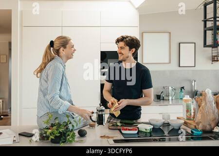 Happy young couple making breakfast together in kitchen at home Stock Photo