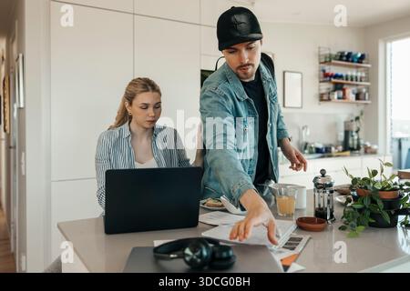 Young woman using laptop near boyfriend preparing to leave for work Stock Photo
