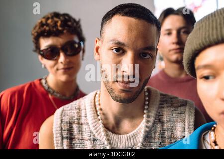 Portrait of serious young man surrounded by multiracial friends Stock Photo