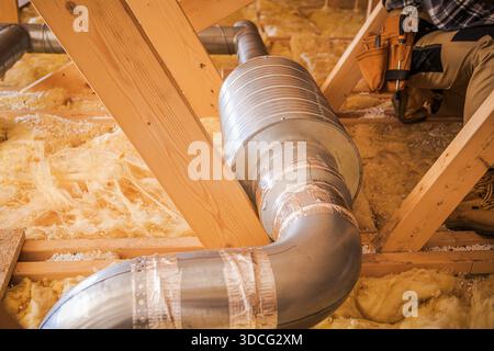 Workers are installing metal ductwork in an attic for a heating system upgrade. Stock Photo