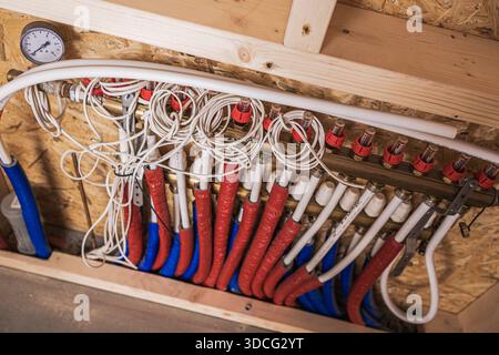 Pipes and valves hang on the wall in a construction area during the heating system installation process. Stock Photo