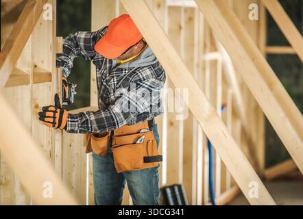 Worker in safety gear builds a wall using tools at a construction site during the day. Stock Photo