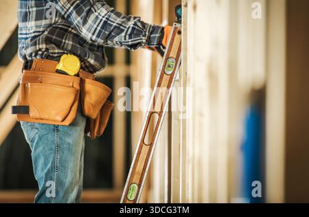 Construction worker uses a tool to check the level of a wall while building indoors. Stock Photo