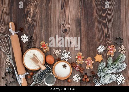 Bowls with flour, sugar, and an egg sit on a wooden table with gingerbread cookies and festive сhristmas decorations. Top view. With space for your te Stock Photo