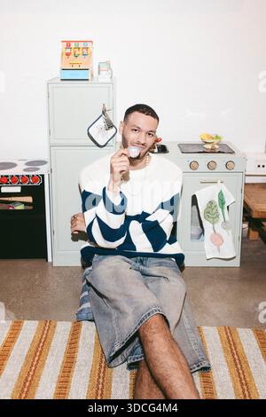 Portrait of young man sitting on floor near model kitchen Stock Photo
