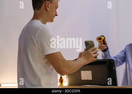 Staff uses scanner on mobile device presented by customer over service desk Stock Photo