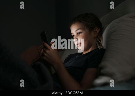 Girl using smart phone in bedroom at night Stock Photo