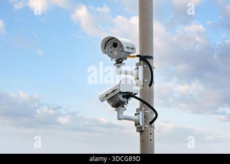 Outdoor surveillance system with dual security cameras mounted on a metal pole for public safety monitoring. Stock Photo