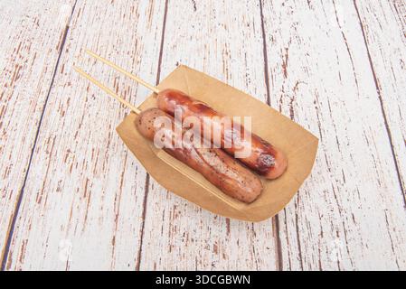 Chinese-style grilled sausages served like lollipops on a wooden table Stock Photo