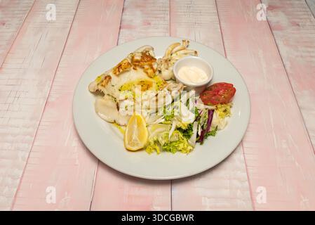 Grilled cuttlefish with aioli, served on a bed of black rice and garnished with strips of roasted red pepper. Stock Photo