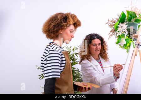 Two women creating art, an experienced painter instructing a young student Stock Photo