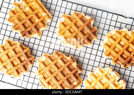Belgian waffles on a metal black rack on a white table. View from above. High quality photo Stock Photo