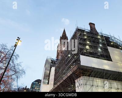 A historic town hall under extensive scaffolding with bright construction lights, reflecting urban restoration in Manchester. Stock Photo