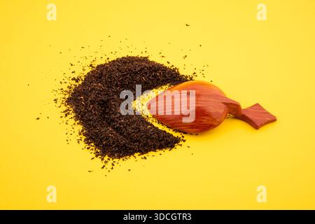 wooden spoon and black tea. dry black tea in wooden spoon on yellow background Stock Photo