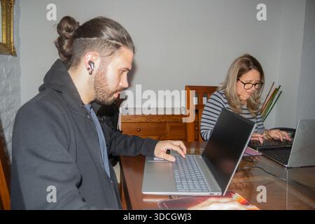 Two colleagues working using laptops and concentrating on their work at the office Stock Photo