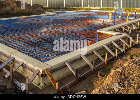 A dense network of underfloor heating pipes arranged on insulated foundation, prepared for concrete pouring during energy-efficient home construction. Stock Photo