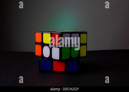 A partially solved Rubik's Cube on a dark surface with a gradient background. Stock Photo