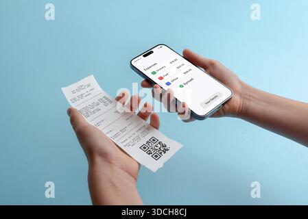 Smartphone displaying expenses overview while holding paper receipt, concept of expense tracking, digital accounting, mobile finance management, and p Stock Photo