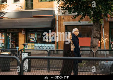 Senior couple walking on sidewalk at street Stock Photo
