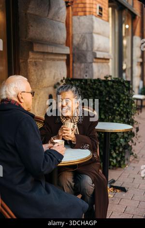 Happy elderly woman spending leisure time with man at sidewalk cafe Stock Photo