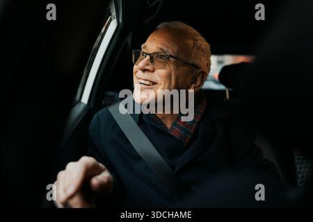 Happy senior man traveling in car while looking out through window Stock Photo