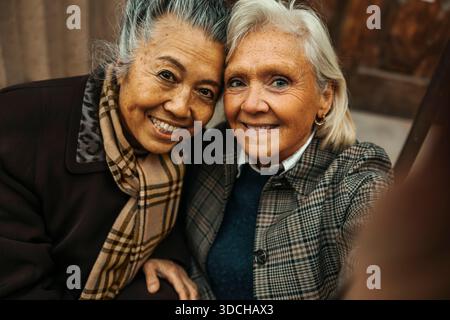 Portrait of smiling senior woman taking selfie with female friend Stock Photo