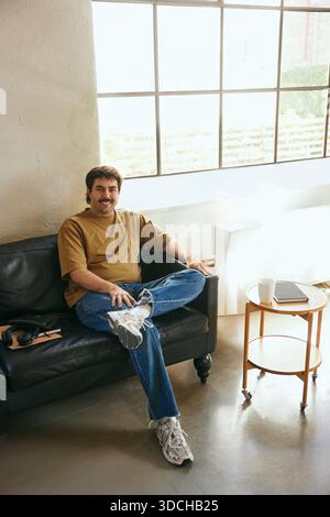 Portrait of confident male entrepreneur sitting on sofa in new office Stock Photo