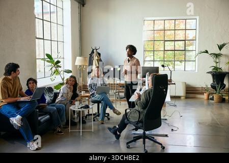 Male and female multiracial colleagues discussing ideas with each other in startup office Stock Photo