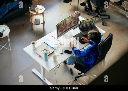 High angle view of male programmer working on desktop PC in tech startup office Stock Photo