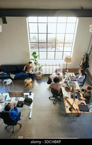 High angle view of multiracial male and female tech experts working on wireless technologies in startup office Stock Photo