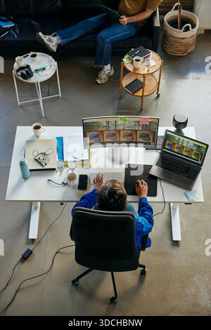 High angle view of male programmer working on desktop PC at desk in tech office Stock Photo