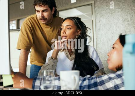 Concentrated female and male tech experts discussing strategies with each other while working on computer in office Stock Photo