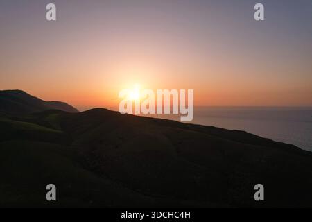 Sun setting over dark hills and the aegean sea in atsiki, lemnos, greece Stock Photo
