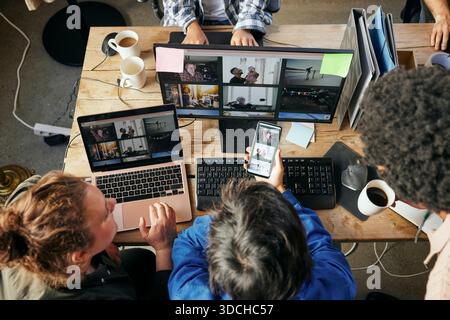 High angle view of male tech professional using different technologies with colleagues while working in office Stock Photo