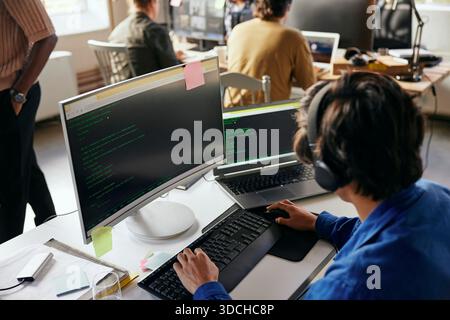 High angle view of young male programmer coding on desktop PC in tech office Stock Photo