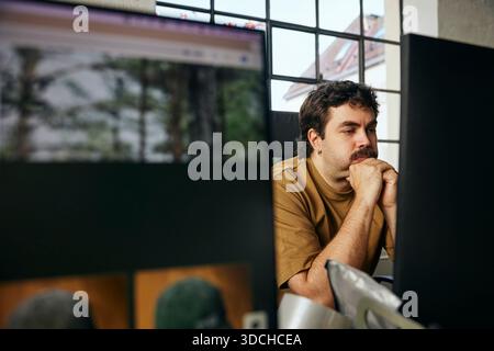 Concentrated businessman leaning on elbows while working in tech office Stock Photo
