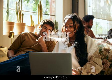 Businessman sitting with female colleague using laptop in tech startup Stock Photo