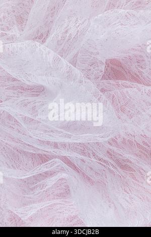 Chic vertical background of white airy guipure with floral ornaments. soft folds of transparent white fabric on a pink background. wedding concept Stock Photo
