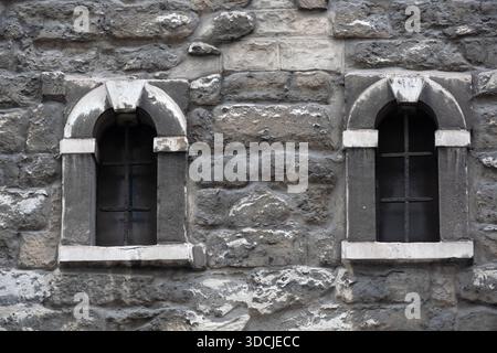 Small arched windows in grey stone church wall for use as a background texture Stock Photo