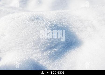 Close-up shot of soft, glittering snow illuminated by sunlight. Frosty crystals and smooth contours create a serene, clean winter background perfect f Stock Photo