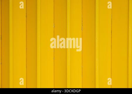 Close-up of a bright yellow corrugated metal surface door featuring uniform vertical ridges and stripes, normally shows on Malaysian shophouse. Stock Photo