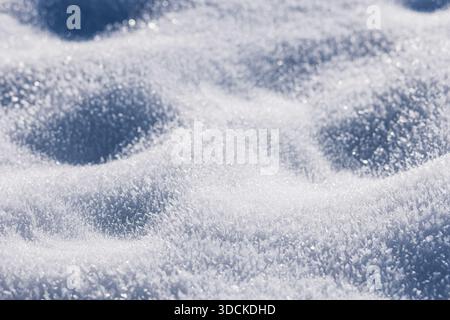 Detailed macro texture of glistening white snow. A cold winter background featuring soft drifts, deep blue shadows, and sparkling crystalline frost. W Stock Photo