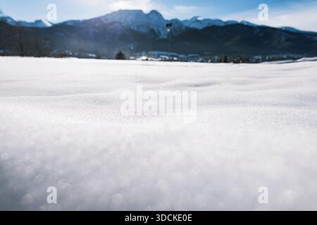 Alpine winter resort scenery featuring ski slopes, snow cannons, and chairlifts, with a backdrop of the majestic, snow-capped Tatra Mountains under a Stock Photo