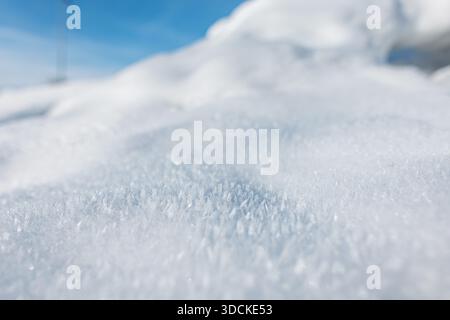 Bright winter snow with shimmering ice crystals reflecting the sun. Smooth mounds and soft shadows highlight the clean, tranquil beauty of a snowy lan Stock Photo