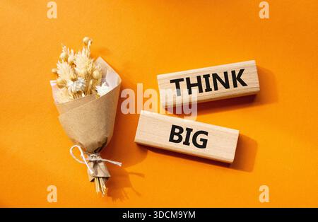 Think big symbol. Wooden blocks with words Think big. Beautiful orange background. Business and Think big concept. Copy space. Stock Photo