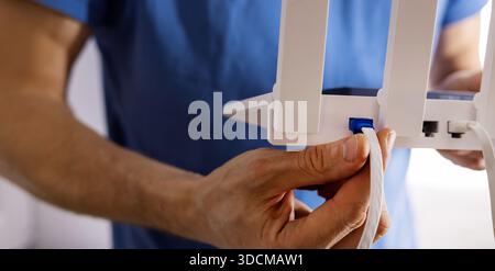 Wireless internet. Service technician installing Wi-Fi router. Connecting LAN cable. copy space Stock Photo